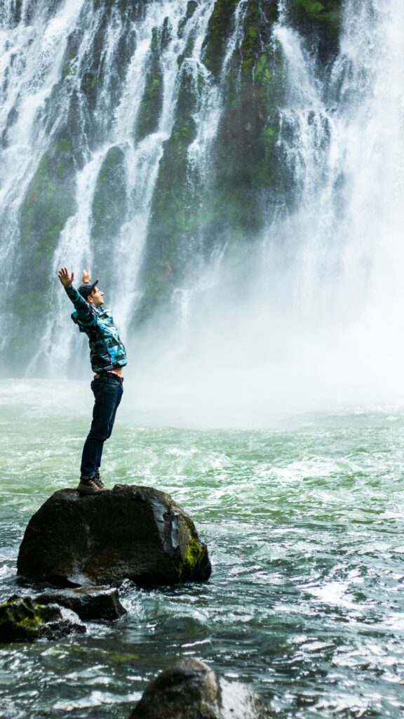 Man on Rock by Waterfalls by Slav Romanov